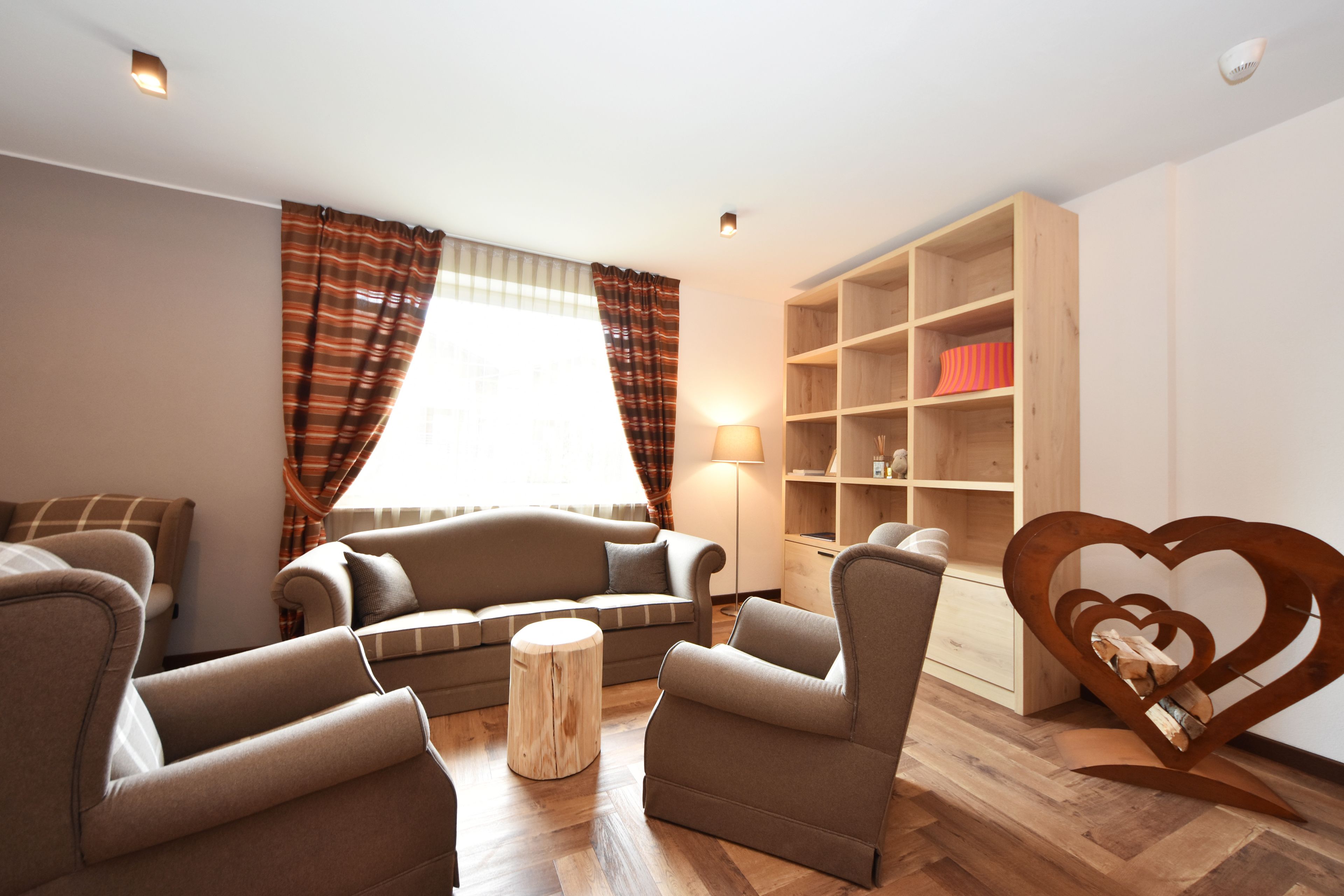 A living room with a sofa set, a coffee table, a wooden bookshelf, and a heart-shaped bookshelf.