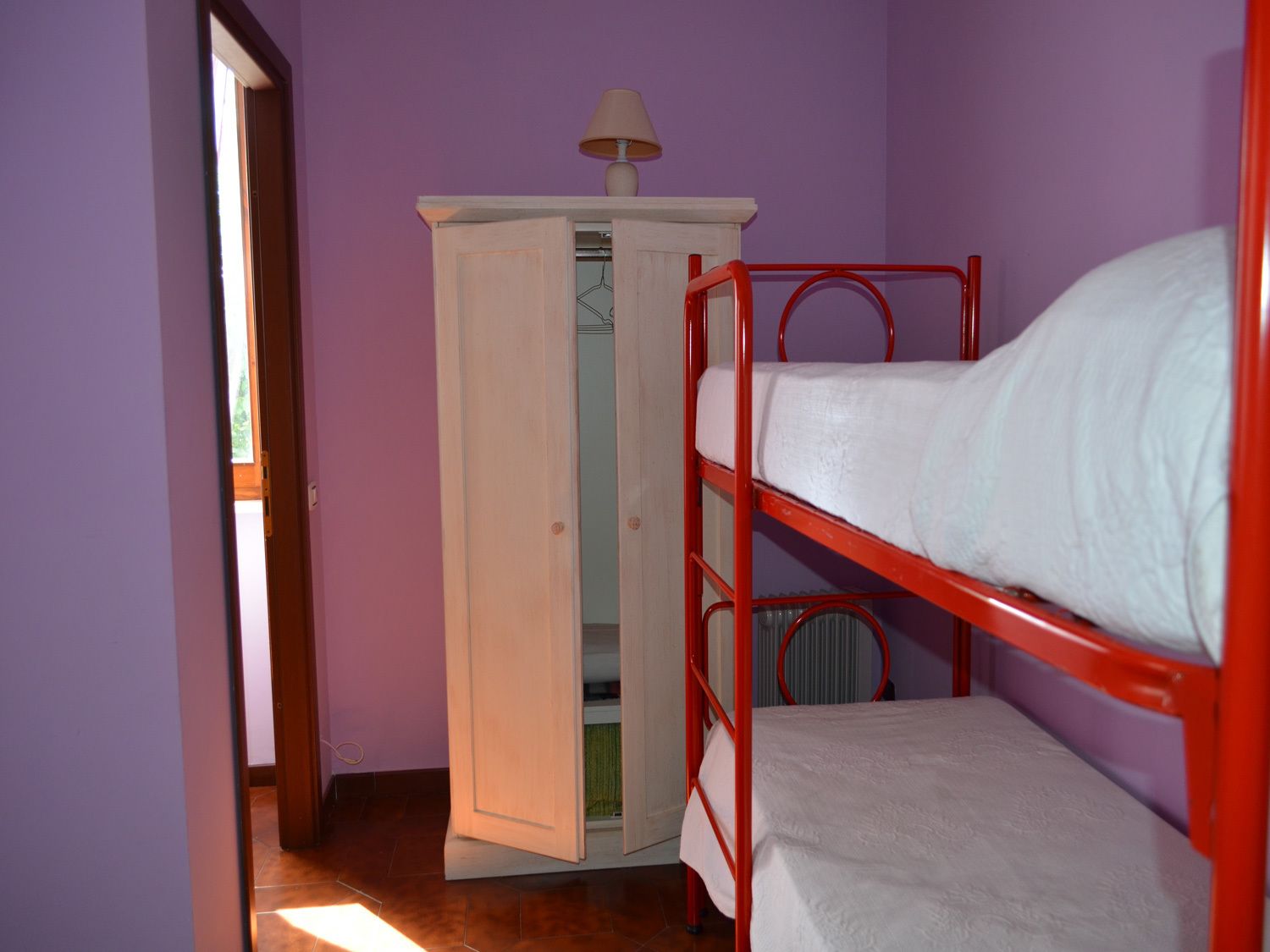 Una habitación con una cama litera, un armario y una lámpara.