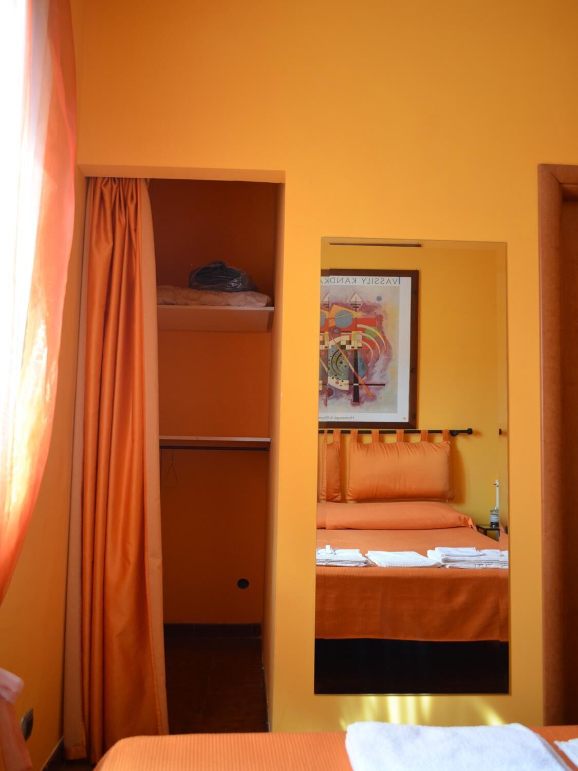 Una stanza con un letto a castello, un letto singolo, uno specchio e un quadro appeso al muro.