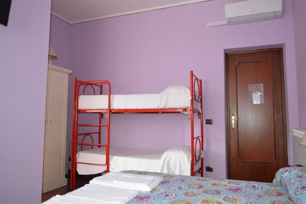Una habitación con una litera, una puerta de madera y un equipo de aire acondicionado blanco en la pared.