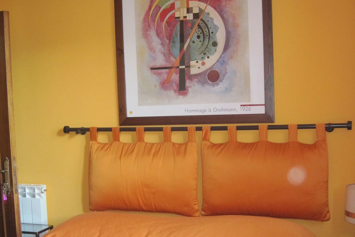 Habitación de hotel con cama, una obra de arte enmarcada en la pared y una ventana con cortinas.