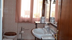 Een badkamer met toilet, wastafel en raam voorzien van gordijnen.