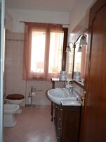 Un baño con inodoro, lavabo y ventana con cortinas.