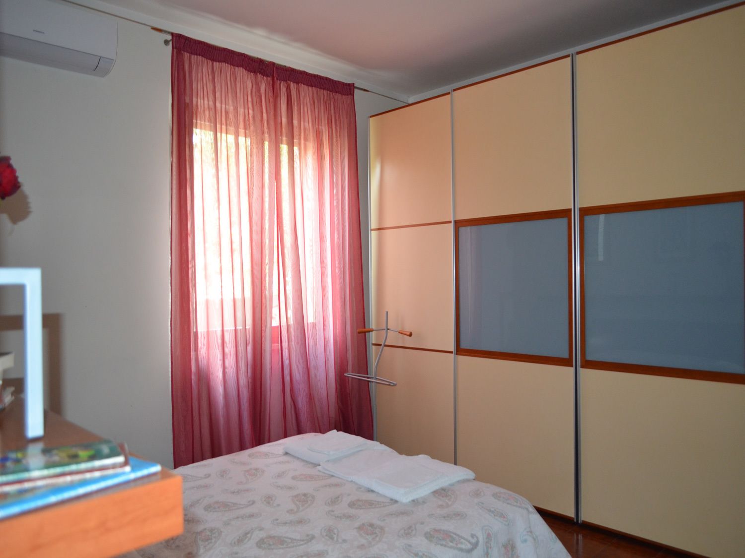 A bedroom with a bed, a wardrobe, and a window with curtains.