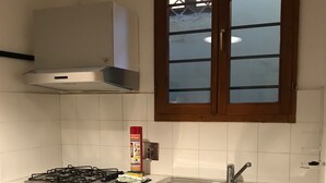 Une cuisine équipée d’une cuisinière à gaz, d’un évier en acier inoxydable et d’une fenêtre avec des panneaux en verre dépoli.