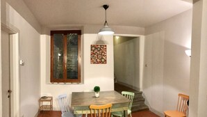 Un coin repas avec une table en bois, quatre chaises, une petite plante et un luminaire suspendu.