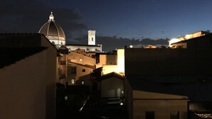 Une vue nocturne d’une ville, avec des bâtiments illuminés et une imposante structure en forme de dôme en arrière-plan.