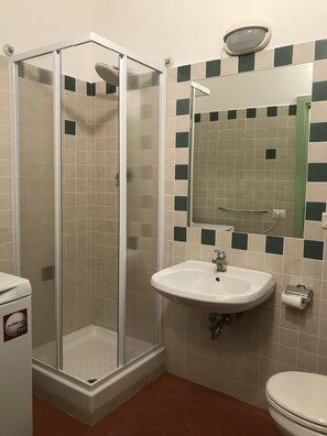 A bathroom with a glass-enclosed shower, a sink with a mirror above it, and a toilet. - Alfani 2P (Florence)