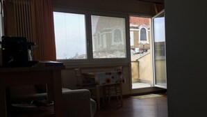 Une pièce comprenant une table à manger et des chaises, un canapé et une fenêtre avec des stores.