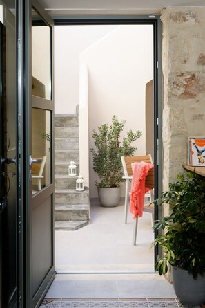 A narrow outdoor corridor with a wooden chair, a potted plant, and a small table with a book. - Casa Teresa (Chania)