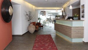 A modern hotel lobby with a reception desk, seating area, and a large vase. - Hotel Pfälzer Hof (Edenkoben)