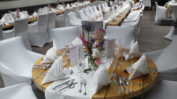 A banquet hall with round tables set for a formal event, each with white chairs, silverware, and floral centerpieces. - Hotel Pfälzer Hof (Edenkoben)