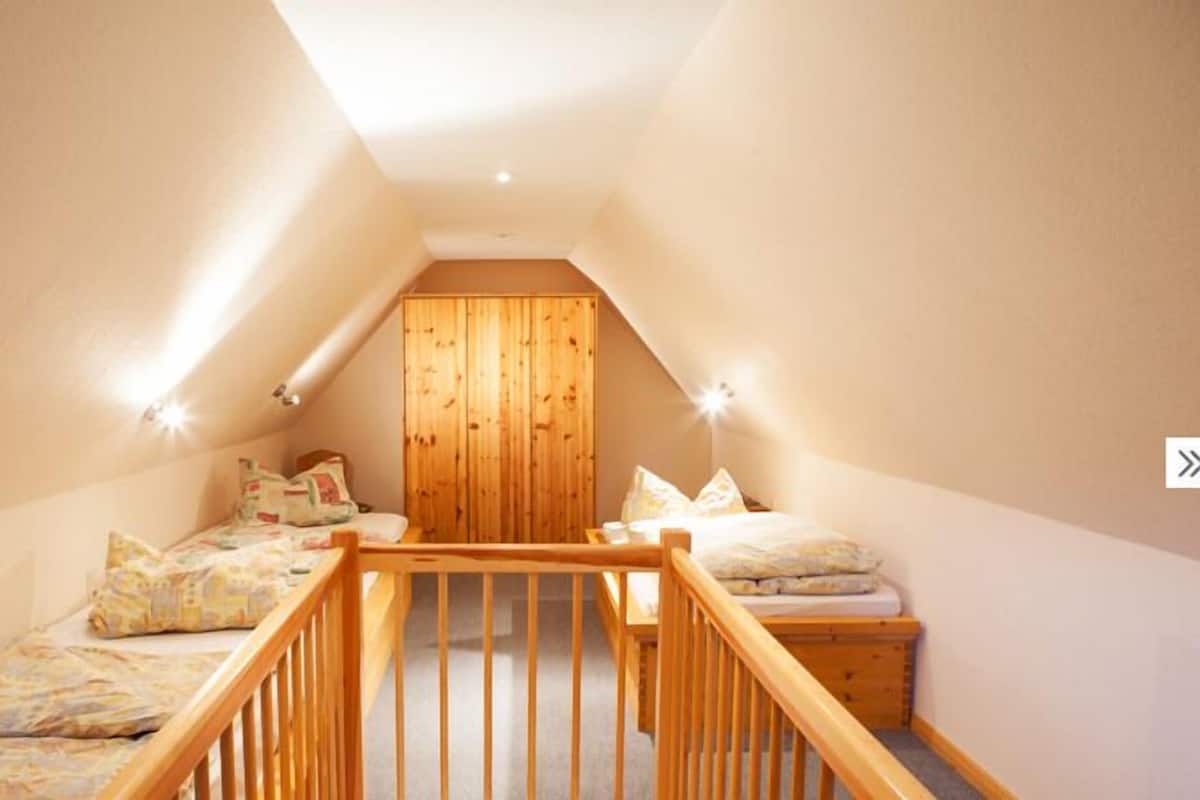 Un dormitorio estilo ático con dos camas, paredes de madera y techo inclinado.