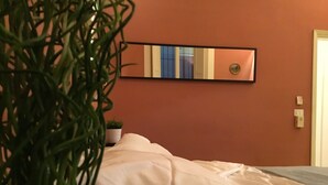 A room with a bed, a potted plant, a wall-mounted mirror, and a small plant on a nightstand. - Battistero (Florence)