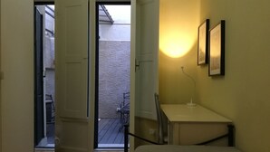 A hotel room with a bed, a desk, a chair, and a small balcony with a table and chairs. - Battistero (Florence)