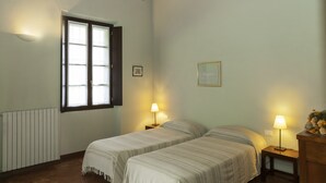 A room with two beds, a window, a radiator, and two bedside lamps. - Agriturismo Cascina Scanna (Cisliano)