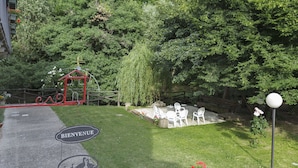 A garden area with a welcome sign, outdoor seating, and a small red structure. - Agriturismo Cascina Scanna (Cisliano)