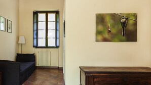 A room with a wooden cabinet, a black sofa, a radiator, and a window with blinds. - Agriturismo Cascina Scanna (Cisliano)