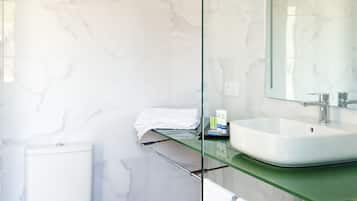 A modern bathroom with a white toilet, a glass shower enclosure, and a marble-tiled wall.