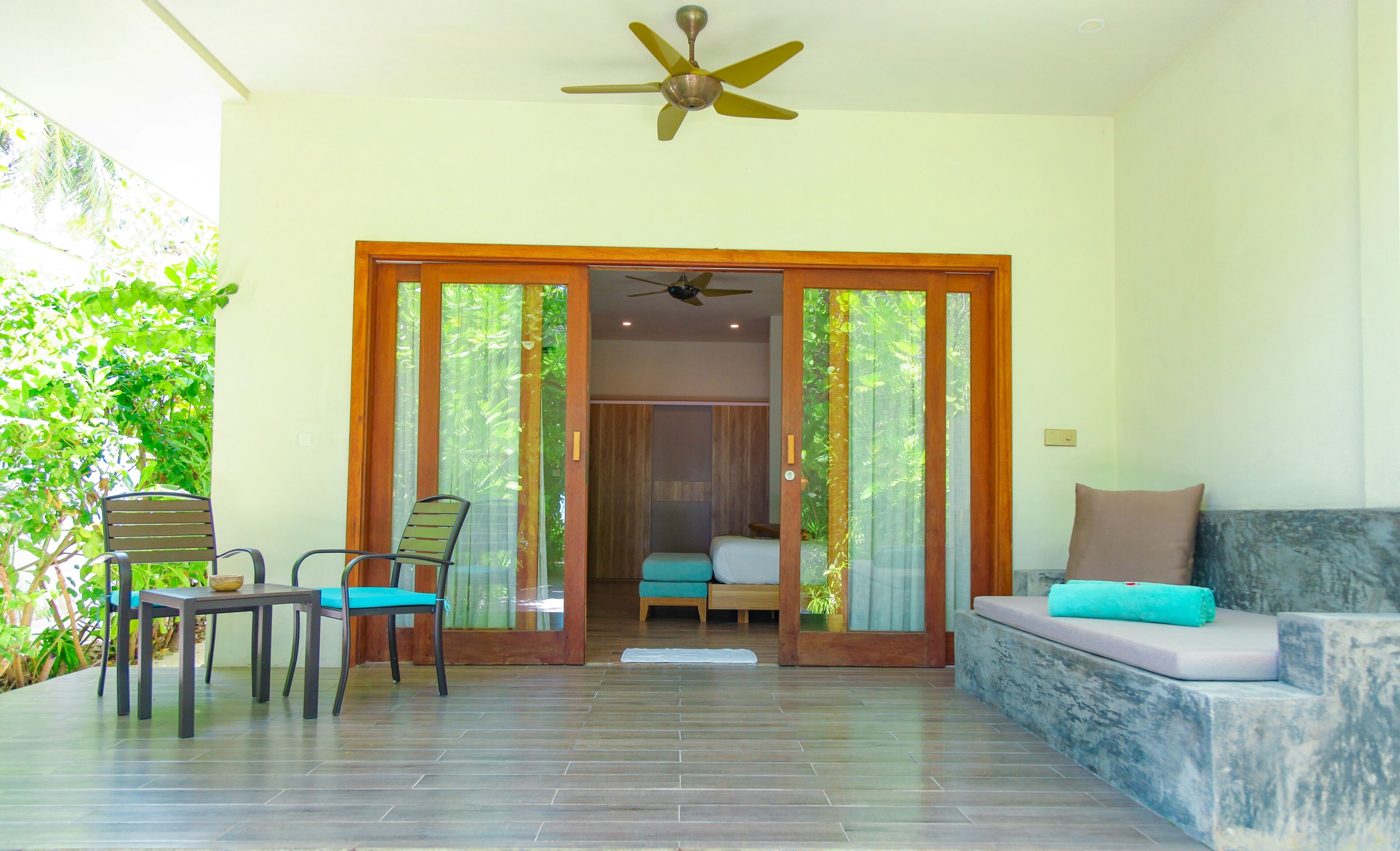 A room with a bed, a sofa, a dining table with chairs, and a ceiling fan.