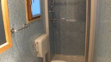 Un baño con inodoro, lavamanos y cabina de ducha.
