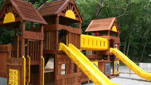 A wooden play structure with two slides and a climbing area. - Campeggio Valle Gesso (Entracque)