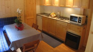 A compact kitchen with wooden cabinets, a microwave, and a sink. - Campeggio Valle Gesso (Entracque)