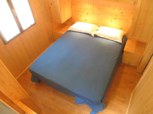 A small, wooden room with a single bed, a window, and a wooden floor. - Campeggio Valle Gesso (Entracque)