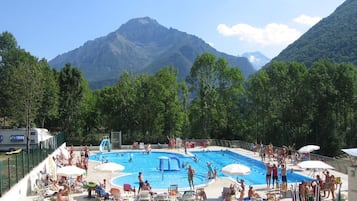 Una piscina al aire libre, sombrillas, sillones reclinables de piscina