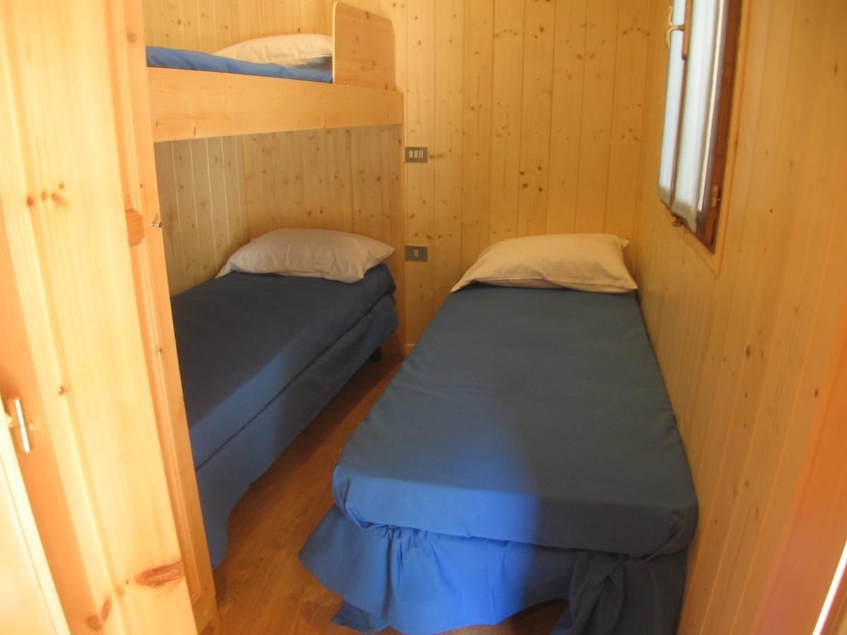 A small, wooden cabin with two bunk beds and a single bed.