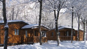 A row of wooden cabins with a covered porch and a snow-covered landscape. - Campeggio Valle Gesso (Entracque)