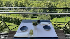 Een eettafel buiten, met uitzicht op een bebost dal.