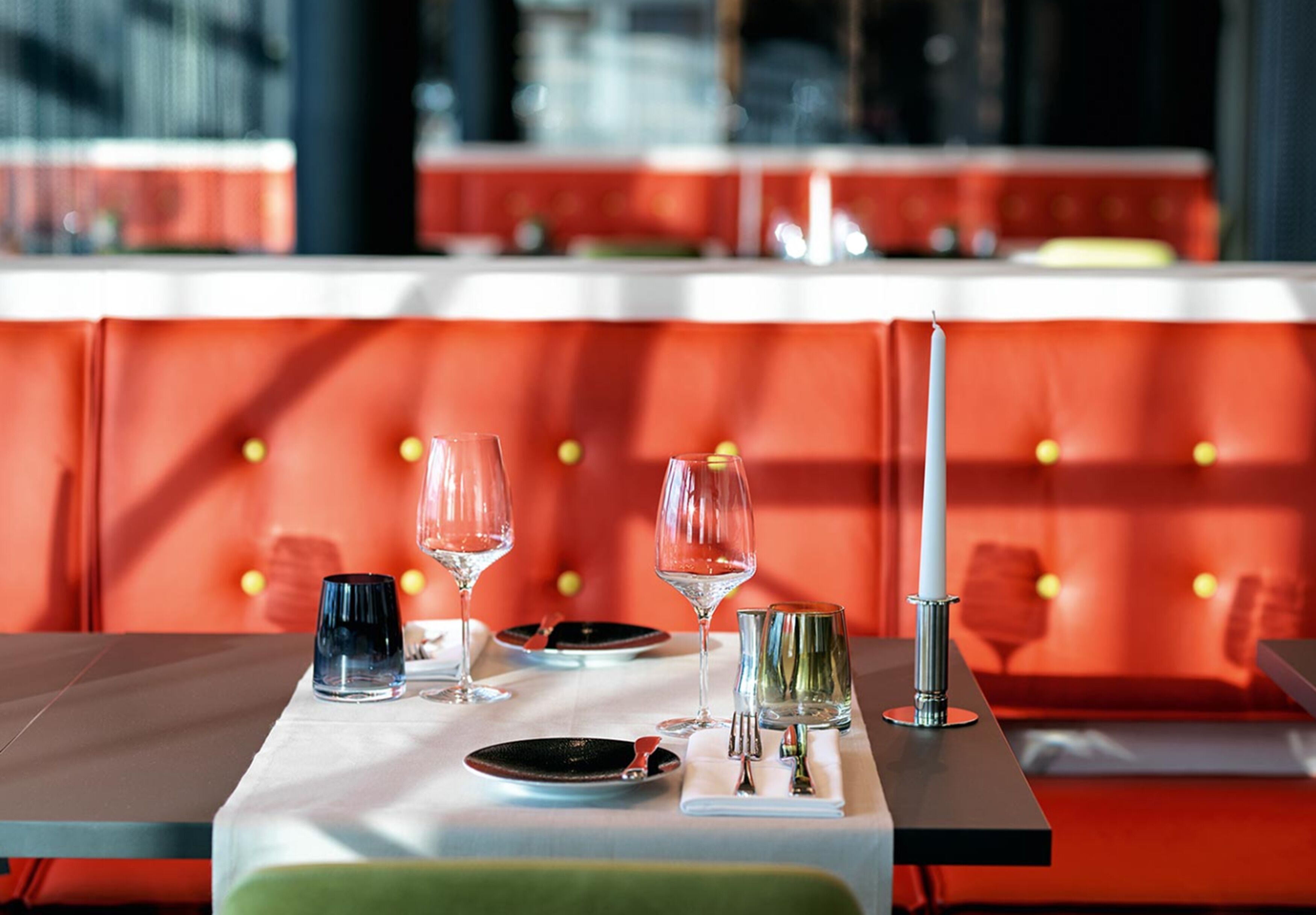 A restaurant setting with a table set for two, featuring a white tablecloth, plates, glasses, and cutlery.