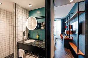 Un baño moderno con un espejo grande, un lavamanos y una ducha.