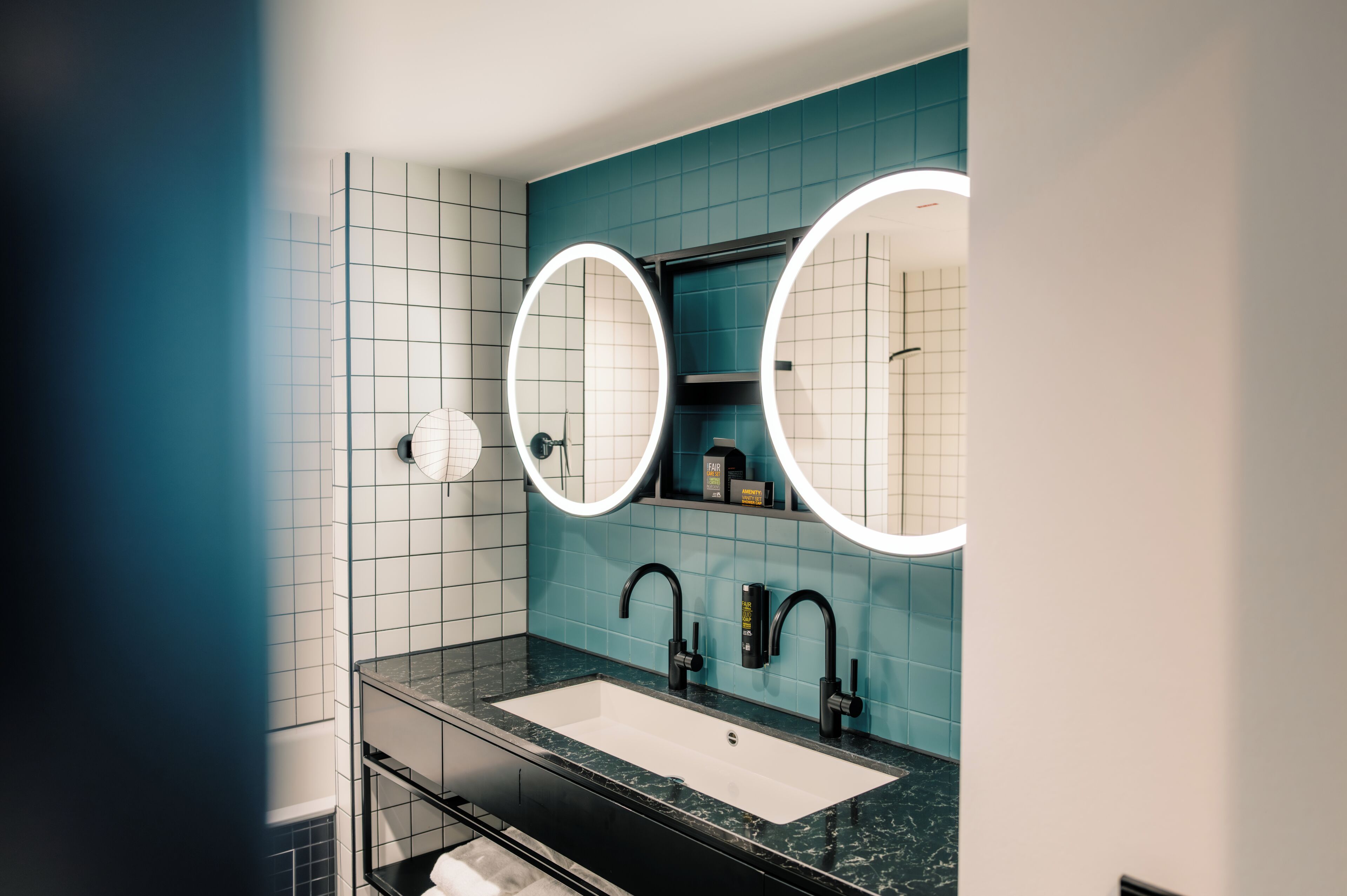 A modern bathroom with a large mirror, two sinks, and a vanity.