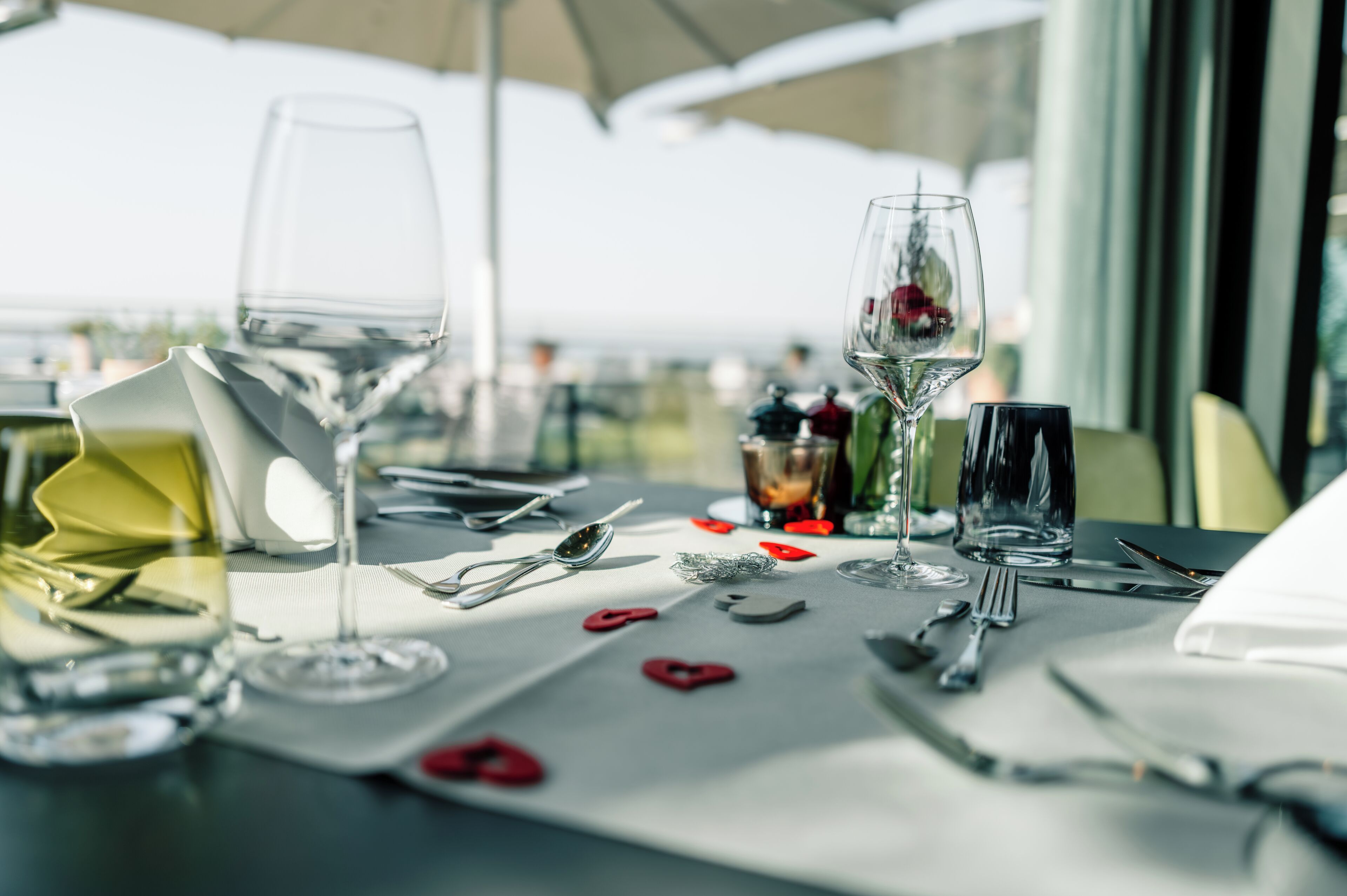 A table set for dining with wine glasses, cutlery, and a dessert.