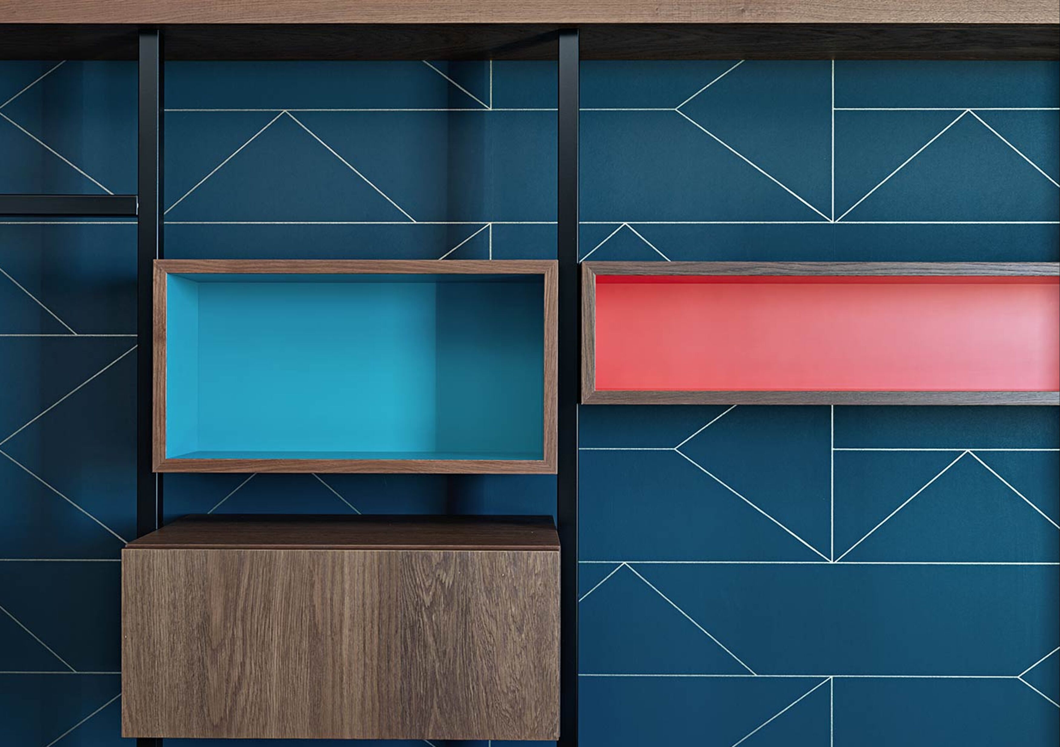 Una pared con diseños geométricos y tres estantes de madera de diferentes alturas.