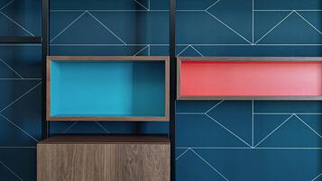 A wall with geometric patterns and three wooden shelves of different heights.