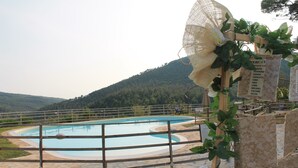 Una piscina amb una tanca de fusta, envoltada de rajoles de pedra i vegetació.