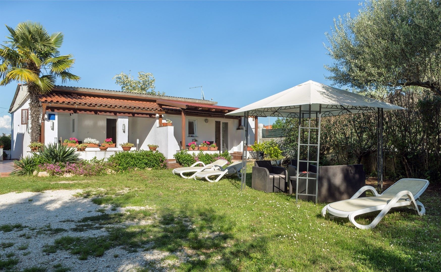 A villa with a patio, outdoor seating, and a garden.