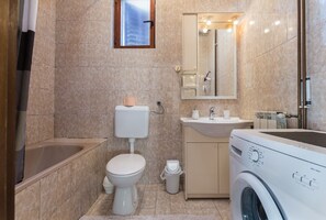 A bathroom with a toilet, sink, mirror, and washing machine.