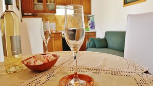 Mesa de jantar com uma garrafa de vinho branco, duas taças de vinho e uma tigela de petiscos.