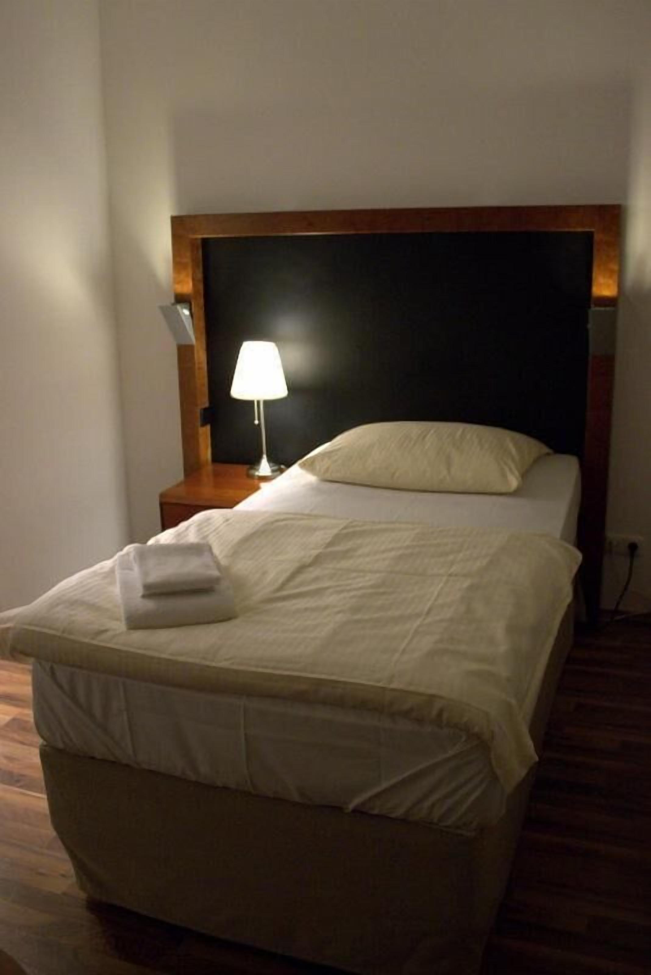 A neatly made bed with a white comforter and a folded towel on the footboard.