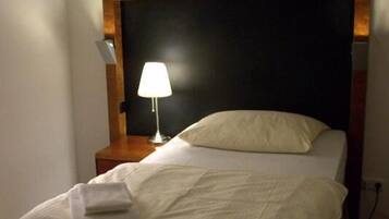 A neatly made bed with a white comforter and a folded towel on the footboard.
