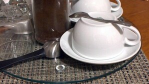 A dining table with a coffee pot, teapot, cups, and a spoon. - Porschepension (Wolfsburg)