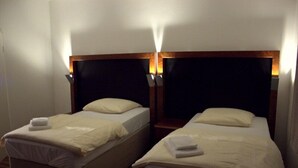 Two single beds with wooden headboards and white linens, each with a bedside lamp. - Porschepension (Wolfsburg)