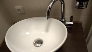 A white sink with a chrome faucet in a bathroom. - Porschepension (Wolfsburg)