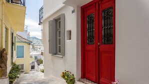 Una calle estrecha con una puerta roja y una estatua a la izquierda.