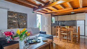 Una sala de estar acogedora con un sofá, una mesa de centro y un jarrón de flores. Hay una zona de cocina con armarios de madera y una mesa de comedor.