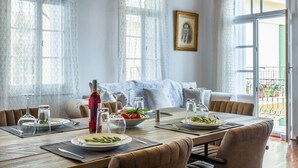Un comedor con una mesa preparada para cuatro personas, una botella de vino tinto y un cuadro en la pared.